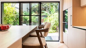 Eine moderne Küche mit einem großen Fenster, Holzkstühlen und einer Schüssel Äpfel.