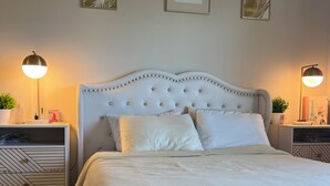 A neatly made bed with a tufted headboard, two bedside tables with lamps, and framed wall art. - Beautiful 1-bedroom apartment in Hollywood with AC, pool, gym, Hollywood sign (West Hollywood)