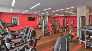 A gym with various exercise equipment, including treadmills, weight machines, and a red carpeted floor. - Beautiful 1-bedroom apartment in Hollywood with AC, pool, gym, Hollywood sign (West Hollywood)