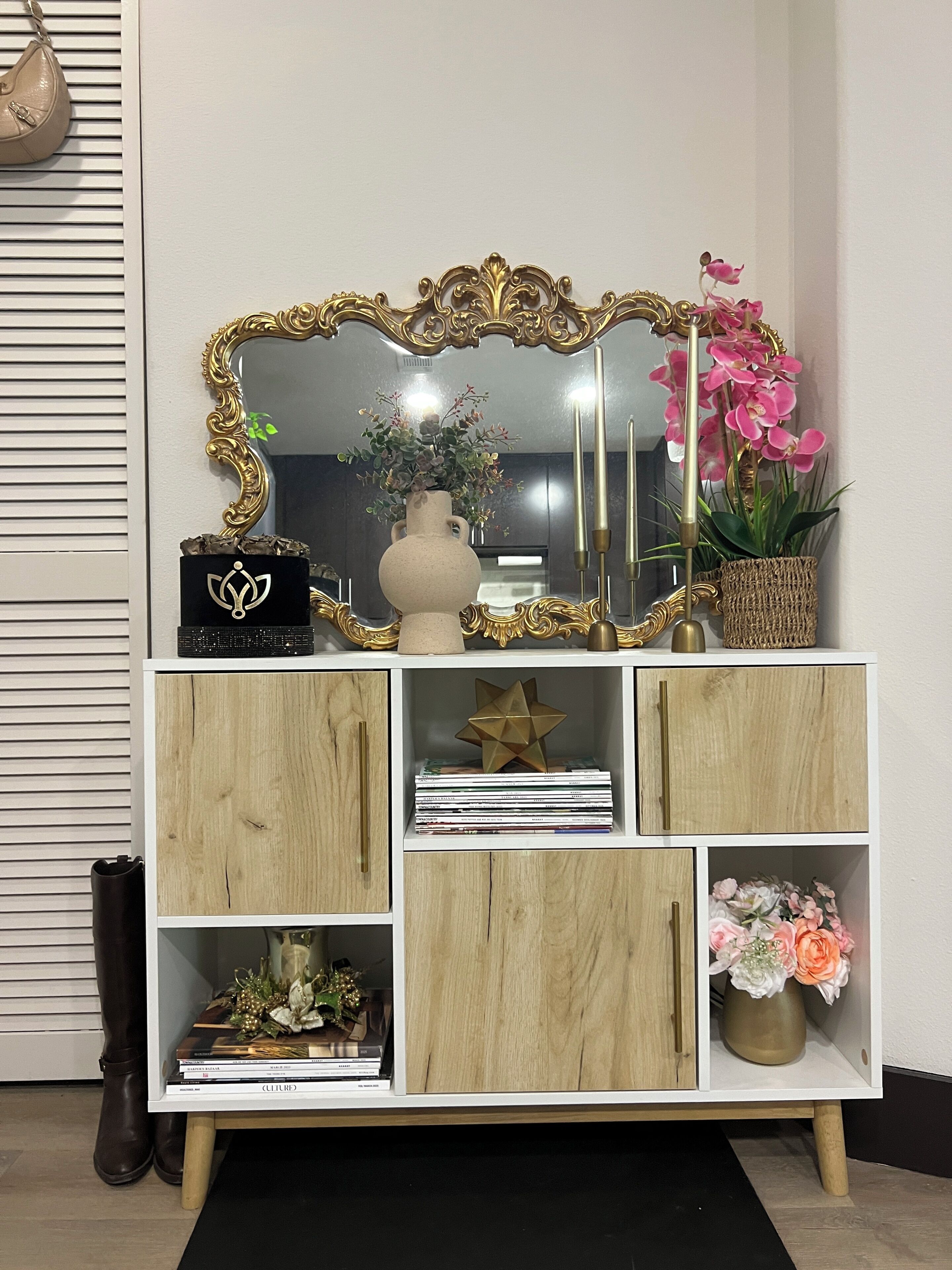 Un meuble blanc en bois orné d’un miroir décoratif, un vase avec des fleurs et un ornement en forme d’étoile.