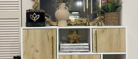 Un meuble blanc en bois orné d’un miroir décoratif, un vase avec des fleurs et un ornement en forme d’étoile.