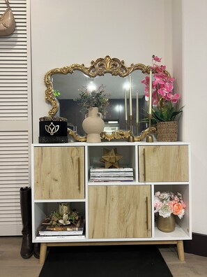 A white wooden cabinet with a decorative mirror, a vase with flowers, and a star-shaped ornament. - Beautiful 1-bedroom apartment in Hollywood with AC, pool, gym, Hollywood sign (West Hollywood)