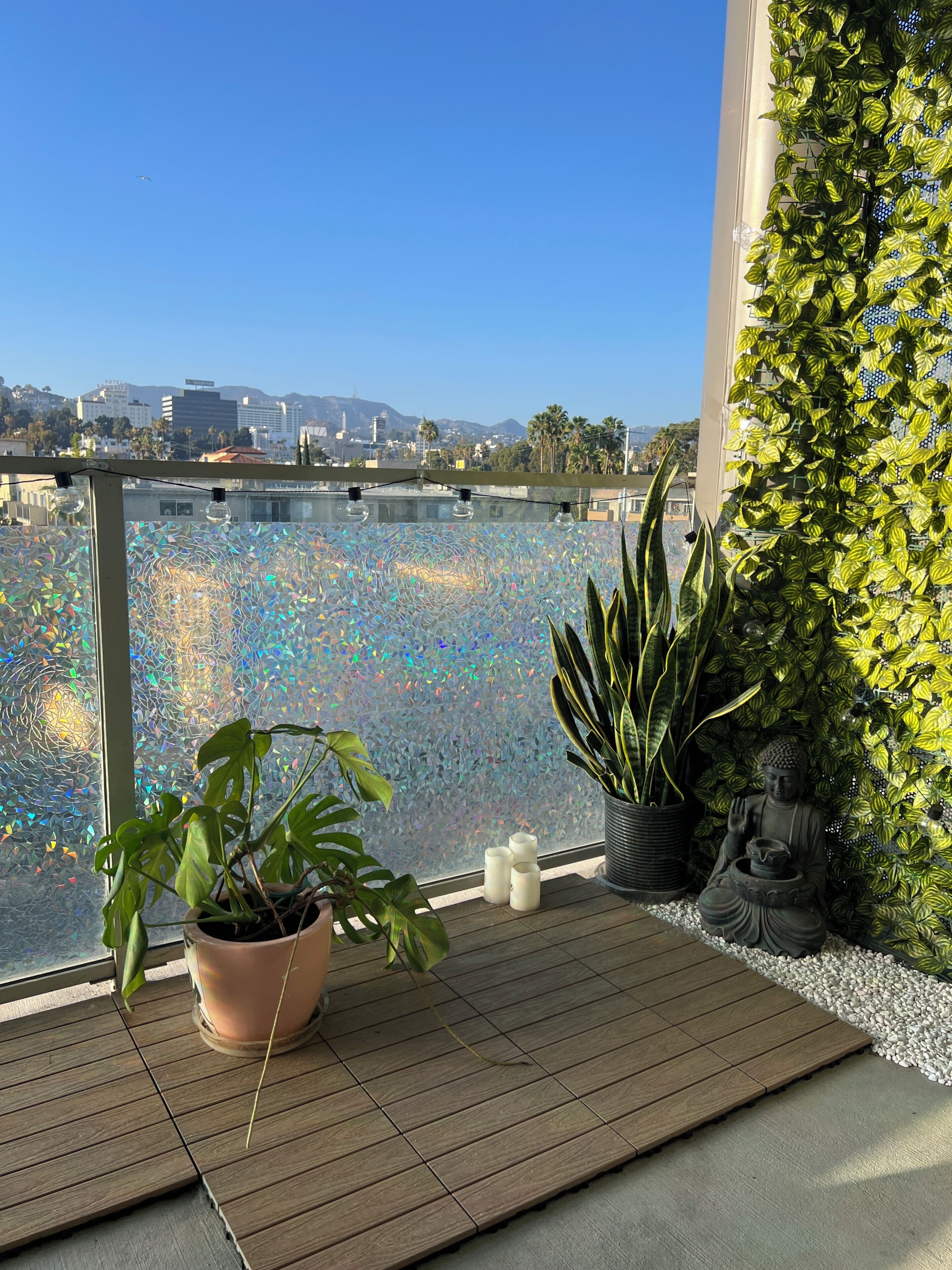 Ein Balkon mit Blick auf ein Gewässer, K übelpflanzen und einer Buddha-Statue.