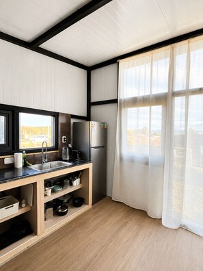 A modern kitchen with a built-in refrigerator, a sink, and a window with sheer curtains. - Modern house with views just steps from Lake Nahuel Huapi (Dina Huapi)