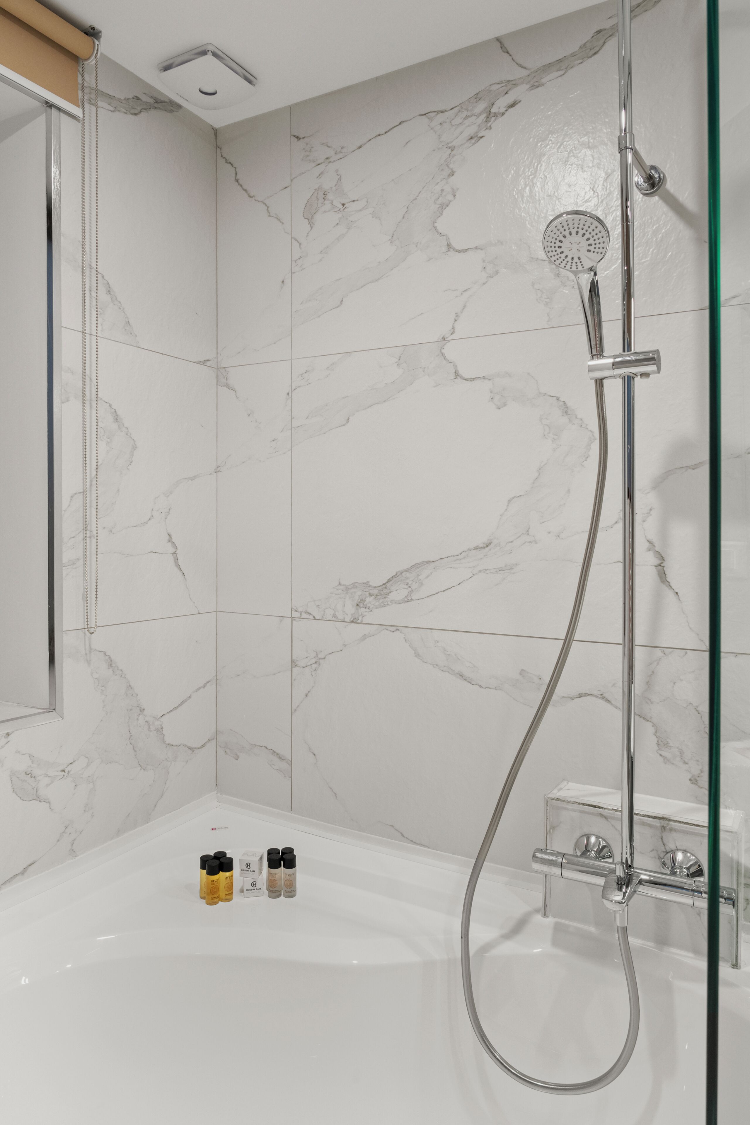 A modern bathroom with a shower, a bathtub, and marble tiles.