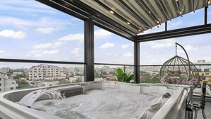 A hot tub with a city view, a hanging plant, and a birdcage.