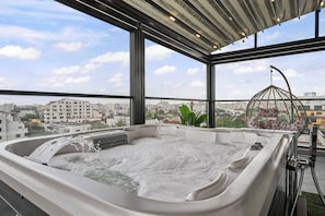 A hot tub with a city view, a hanging plant, and a birdcage. - Crown Penthouse  Luxurious Spa Vista (București)