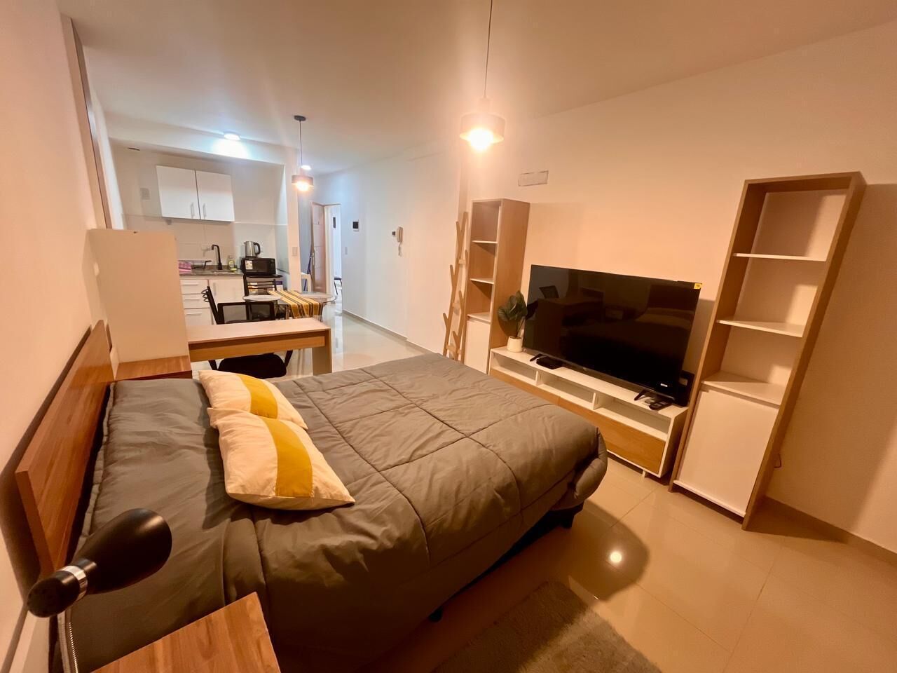 A modern bedroom with a bed, a TV, and built-in shelving.