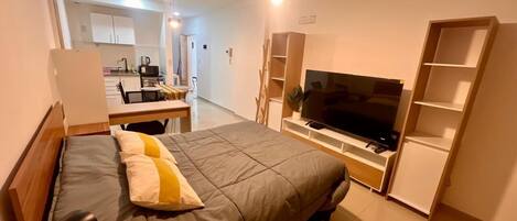 A modern bedroom with a bed, a TV, and built-in shelving.