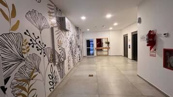 A hallway with patterned wall art, a fire extinguisher, and a door at the end.