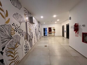 Un couloir orné de motifs décoratifs sur les murs, avec un extincteur et une porte au fond.