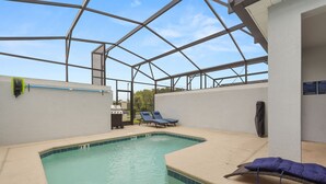 Une piscine dotée d’un espace couvert, de chaises longues et d’un barbecue.
