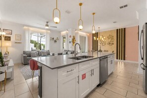 A modern kitchen with a central island, stainless steel appliances, and pendant lighting. - 4 BD/ 3 BA/ Storey Lake (4383 SL) (Kissimmee)