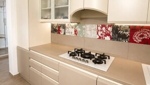 Une cuisine moderne avec des meubles de couleur beige, une cuisinière à gaz et un revêtement mural décoré de motifs floraux.