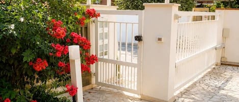 A residential building with a gated entrance, a stone-paved courtyard, and a pergola with plants.