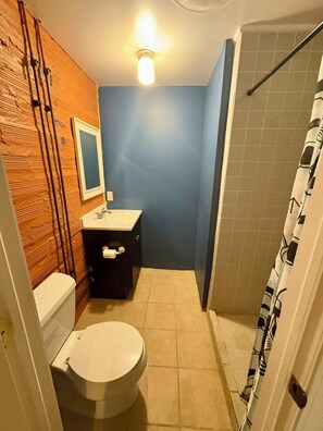 A bathroom with a toilet, sink, and shower.