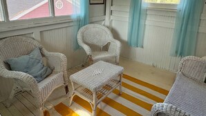 Una habitación con muebles de mimbre, piso a rayas y cortinas en las ventanas.
