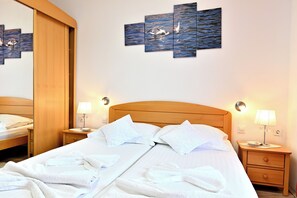 Habitación de hotel con una cama grande, dos mesitas de noche, un cabecero de madera y una decoración mural que representa agua y aves.