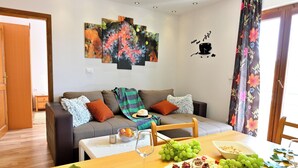Ein Wohnzimmer mit Sofa, einem Esstisch gedeckt mit Speisen und Getränken sowie einer Wand mit abstrakter Kunst.