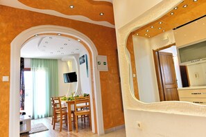 A room with a dining area, a television mounted on the wall, and a door with a mirror. - Bošković-Apartment-2, Modern Family Apartment with Balconies | 2 Bedrooms 6 pers (Rudina)