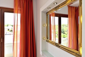 Ein Zimmer mit einem großen Spiegel, einer Tür und einem mit Vorhängen ausgestatteten Fenster.