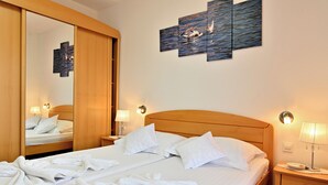 Ein Hotelzimmer mit einem großen Bett, einem hölzernen Kopfteil, einem Nachttisch mit Lampe, einem Wandbild und einem Spiegel.