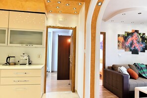 A modern kitchen with a coffee maker, a dining area with a sofa, and a hallway leading to another room. - Bošković-Apartment-2, Modern Family Apartment with Balconies | 2 Bedrooms 6 pers (Rudina)