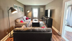 A living room with a sofa, a coffee table, a TV, and a lamp.