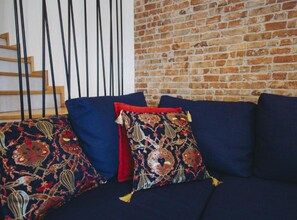 Un divano blu scuro con cuscini decorativi su uno sfondo di muro in mattoni.