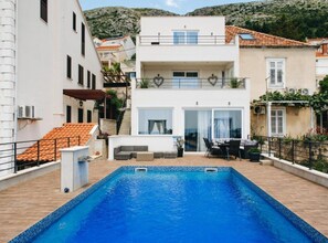 A two-story building with a swimming pool, outdoor seating, and a view of the surrounding area. - Three Bedroom Apartment with Balcony (Dubrovnik)