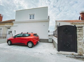 Un'auto rossa parcheggiata di fronte a un edificio bianco con un cancello nero.