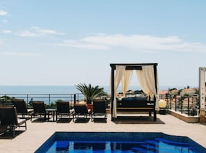 A poolside area with a bed, chairs, and a view of the sea. - Three Bedroom Apartment with Balcony (Dubrovnik)