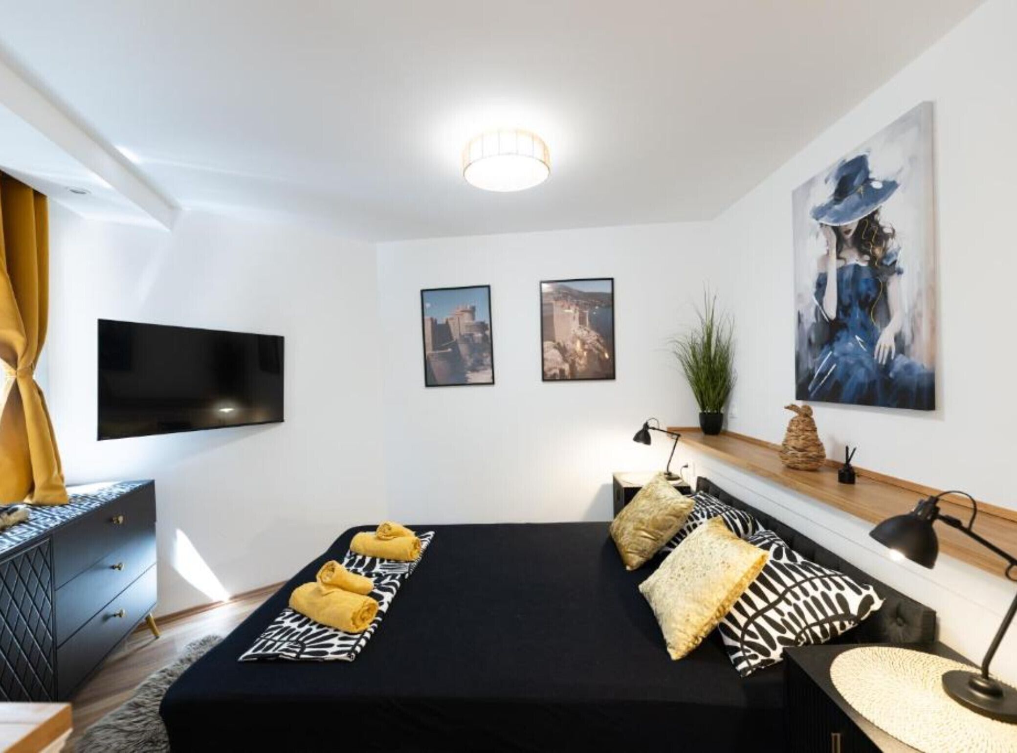 Un dormitorio moderno con cama, televisor de pantalla plana y obras de arte en las paredes.
