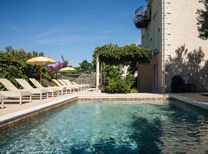 A swimming pool with lounge chairs and umbrellas, surrounded by greenery and a building. - Marghareta Apartment NO 1 - TOP Location - Studio Apartment (Dubrovnik)