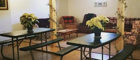Una stanza con tavoli da picnic, sedie e piante in vaso.