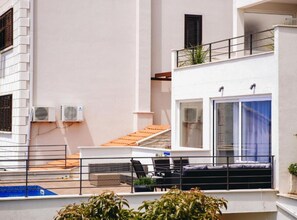 A modern building with a balcony, outdoor seating, and a pool. - Two Bedroom Apartment with Sea View (Dubrovnik)