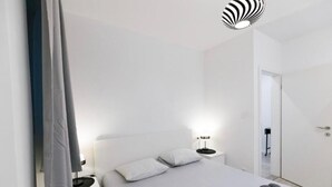 Ein modernes Schlafzimmer mit Bett, Nachttischen, einem Spiegel und einer Tür.