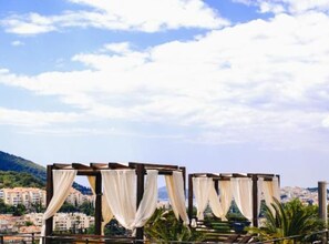 A rooftop terrace with wooden pergolas and white curtains. - Two Bedroom Apartment with Sea View (Dubrovnik)