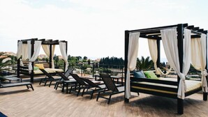 Eine Dachterrasse mit vier Baldakinen, Liegestühlen und einem Pool.