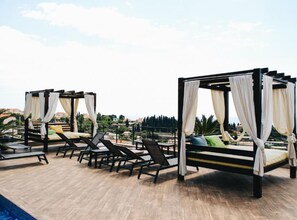 A rooftop terrace with four canopy beds, lounge chairs, and a pool. - Two Bedroom Apartment with Sea View (Dubrovnik)