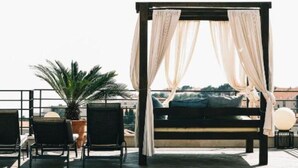 Eine Dachterrasse mit Baldachinbett, Sitzgelegenheit und Topfpflanzen.