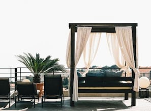 A rooftop terrace with a canopy bed, seating area, and potted plants. - Two Bedroom Apartment with Sea View (Dubrovnik)