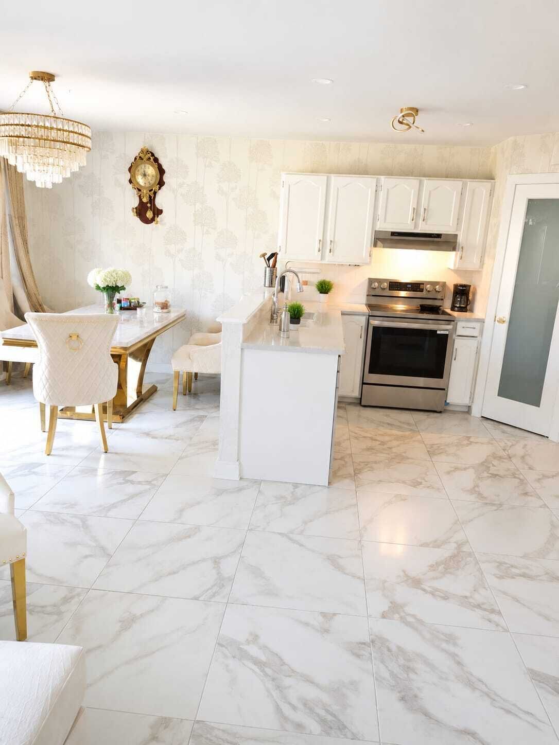 Une cuisine moderne avec des meubles blancs, un sol en marbre et un lustre.