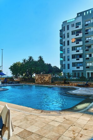 Ein Swimmingpool mit einer Steinmauer und Palmen im Hintergrund.