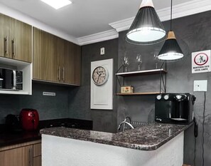 Een keuken met een granieten aanrecht, een koffiezetapparaat en een klok aan de muur.