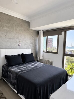 Ein modernes Schlafzimmer mit einem großen Bett, einer Wand aus Beton und Blick auf die Stadt.