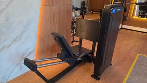 Una màquina d'esquí nòrdic a una sala de gimnàstica amb un paviment de fusta i equip d'exercici al fons.