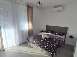 A bedroom with a bed, curtains, a hanging light fixture, an air conditioning unit, and a nightstand. - Villa Bribir (Vinodol)