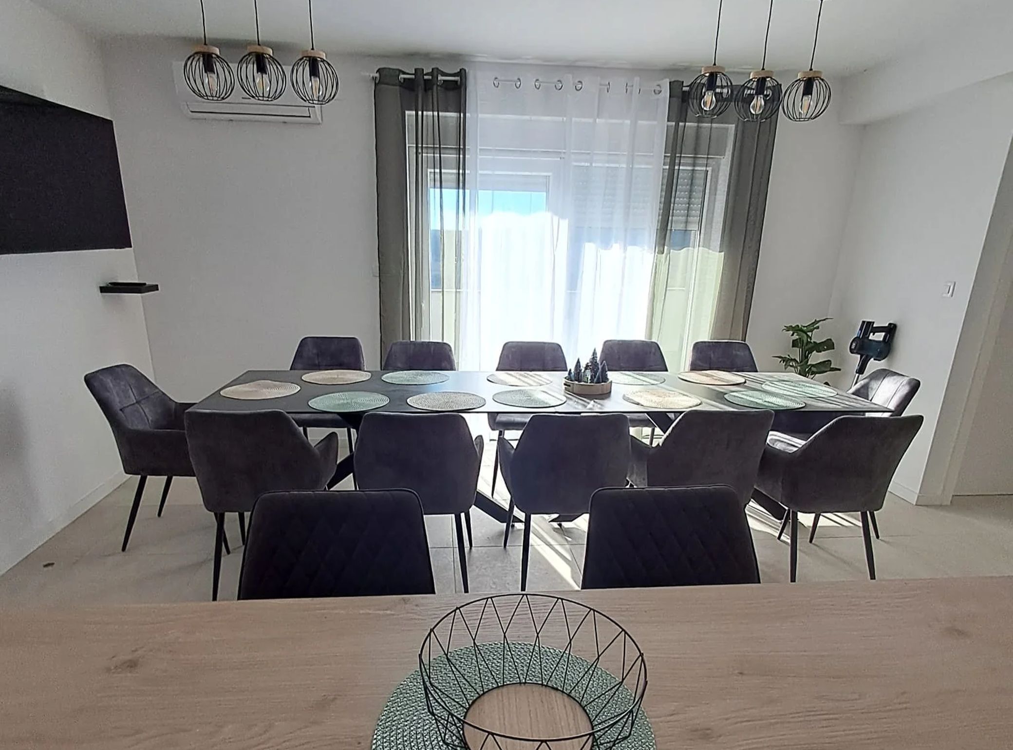 Un espace de salle à manger moderne, doté d’une grande table, de plusieurs chaises et d’un éclairage suspendu.