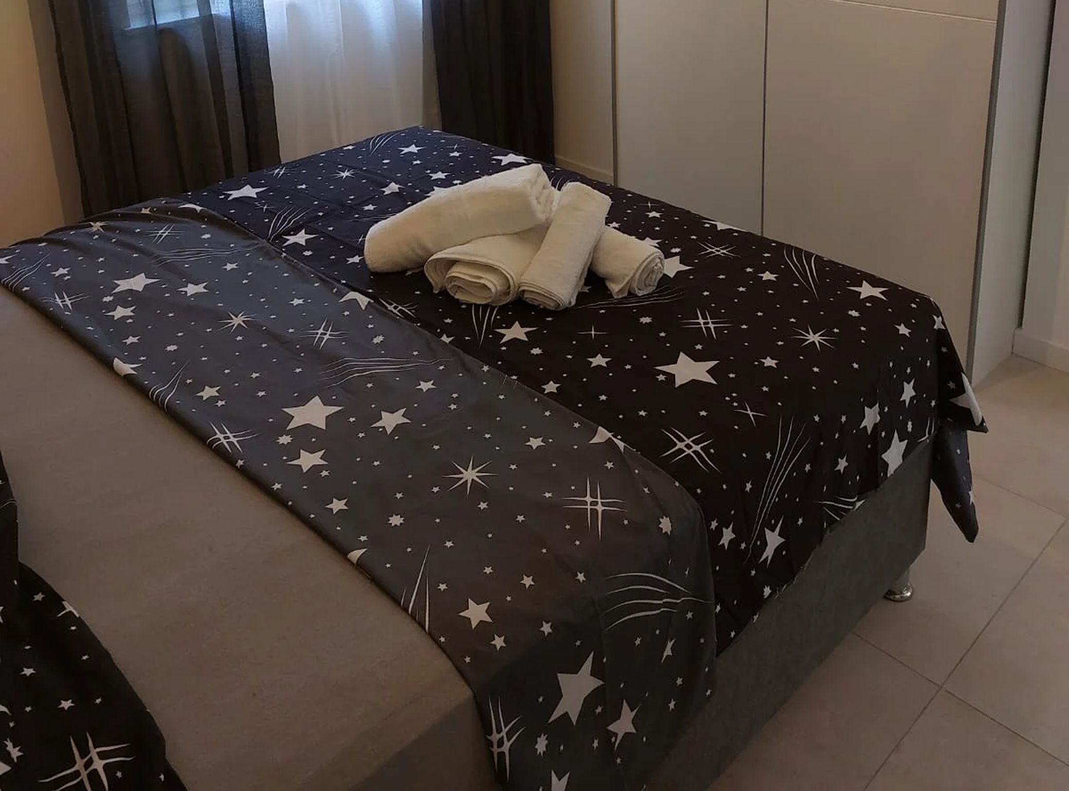 Ein Bett mit einem Bettbezug mit Sternenmuster und ordentlich gefalteten Handtüchern.